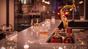 A bar area with glasses of liquor, a tap, and bottles on a marble countertop. - LABE Hôtel Tours Centre Gare (Tours)