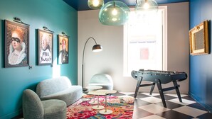 A room with teal walls, a foosball table, a sofa, and a colorful rug. - LABE Hôtel Tours Centre Gare (Tours)