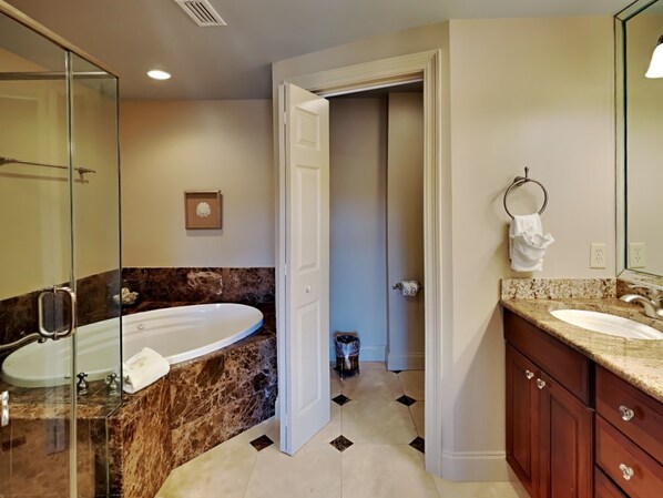 A bathroom with a large bathtub, a glass shower enclosure, and a marble countertop. - Aegean #329 | Community Pool & Tennis + Shuffleboard (Destin)