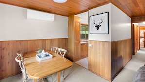 Une pièce aux murs lambrés, comprenant une table à manger, des chaises et un tableau représentant une tête de cerf encadrée.