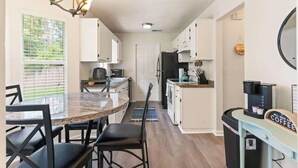 A compact kitchen with a dining area, a coffee station, and a refrigerator. - Creekside Hideaway (Brunswick)
