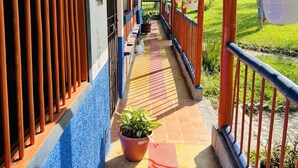 Un couloir couvert doté d’un sol carrelé, de plantes en pot et d’une rambarde.