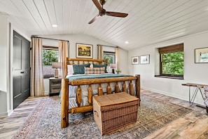A bedroom with a wooden bed, a ceiling fan, a large window, and a rug. - Far Horizons: MtnView•HotTub•PoolTbl•KingSuites (Gatlinburg)