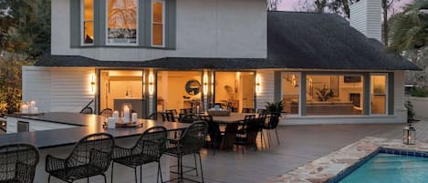 A modern house with a pool, outdoor dining area, and a fireplace.