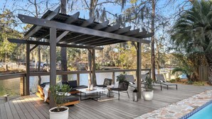 A wooden deck with outdoor seating, a pool, and a view of a lake. - 8BR Lakefront Estate | Pool, Hot Tub & Lake Access (Savannah)