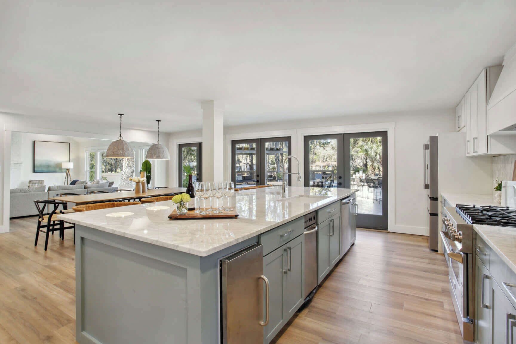 A modern kitchen with a large island, stainless steel appliances, and a view to the outside.