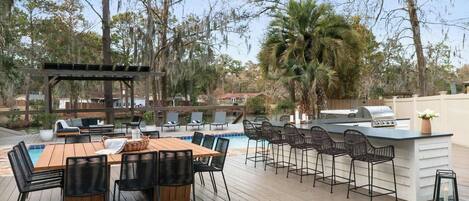 An outdoor patio with a pool, bar, and seating area.