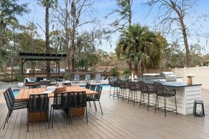 Eine Terrasse im Freien mit Pool, Bar und Sitzbereich.