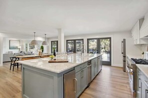 A modern kitchen with a large island, stainless steel appliances, and a view to the outdoors.