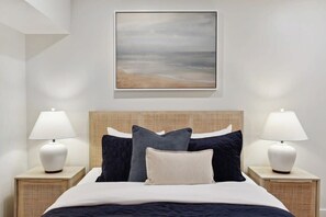 A neatly arranged bedroom with a bed, two bedside tables, and a wall-mounted painting.