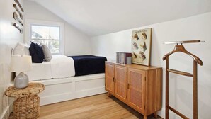 A cozy room with a bed, a wooden cabinet, a hanging rack, and a window with a view. - 8BR Lakefront Estate | Pool, Hot Tub & Lake Access (Savannah)