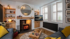 Ein modernes Wohnzimmer mit Kamin, Fernseher und einem großen Spiegel.