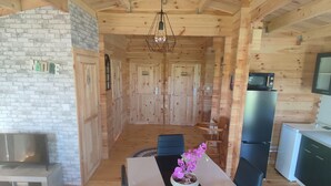 A wooden cabin interior with a dining area, kitchen, and a fireplace.