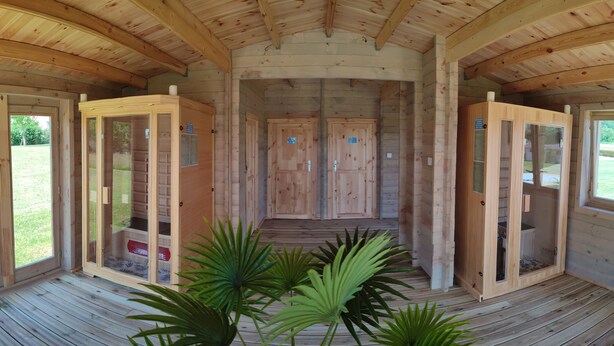 A wooden cabin with a central hallway leading to two doors, each with a small window and a sign.