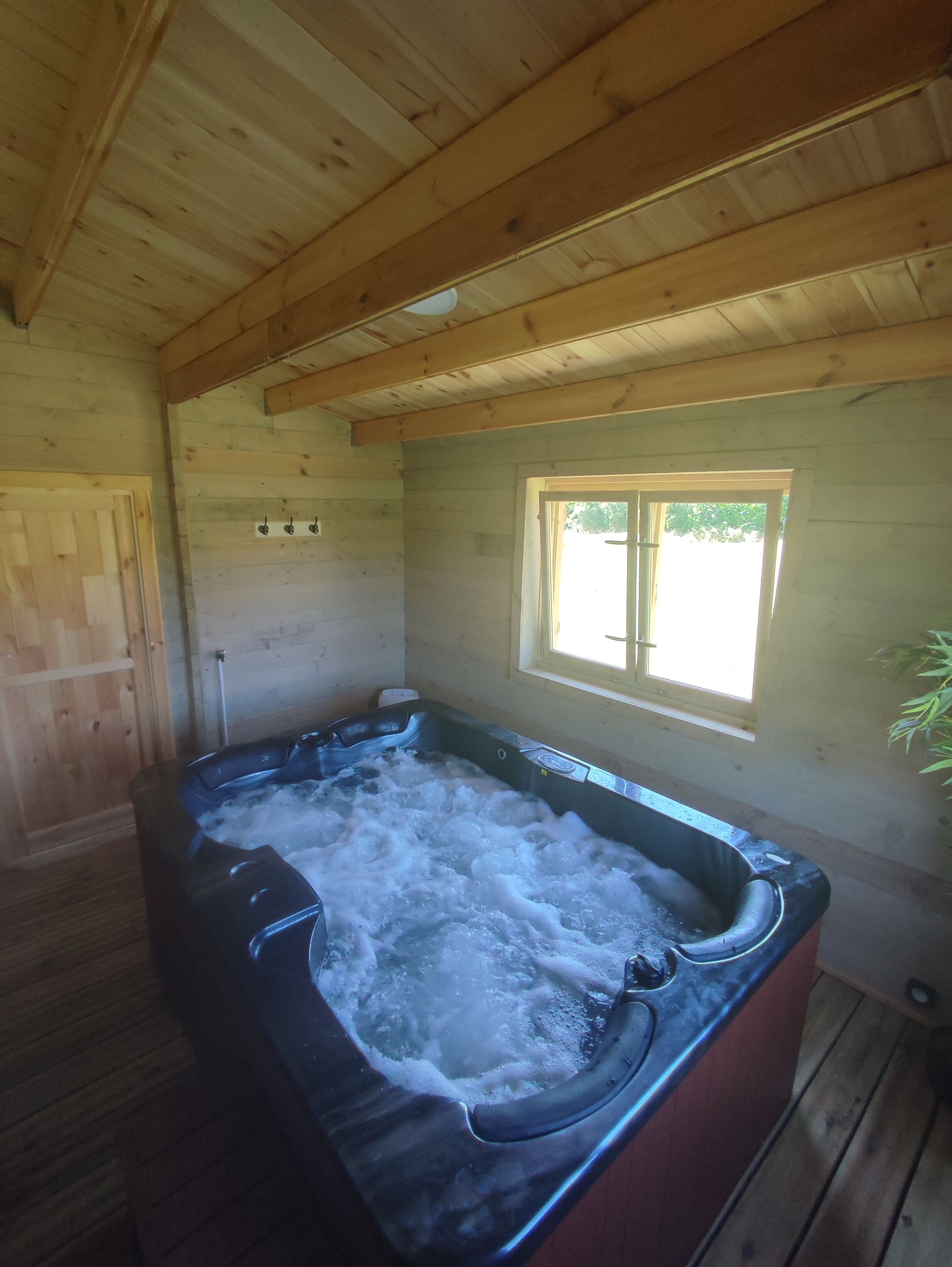 A wooden cabin with a hot tub filled with water.
