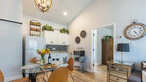 A modern kitchen with white cabinets, a built-in oven, and a dining area with a glass table and chairs. - La Casita: Hot-tub & Firepit, 15 min to Fred! (Harper)