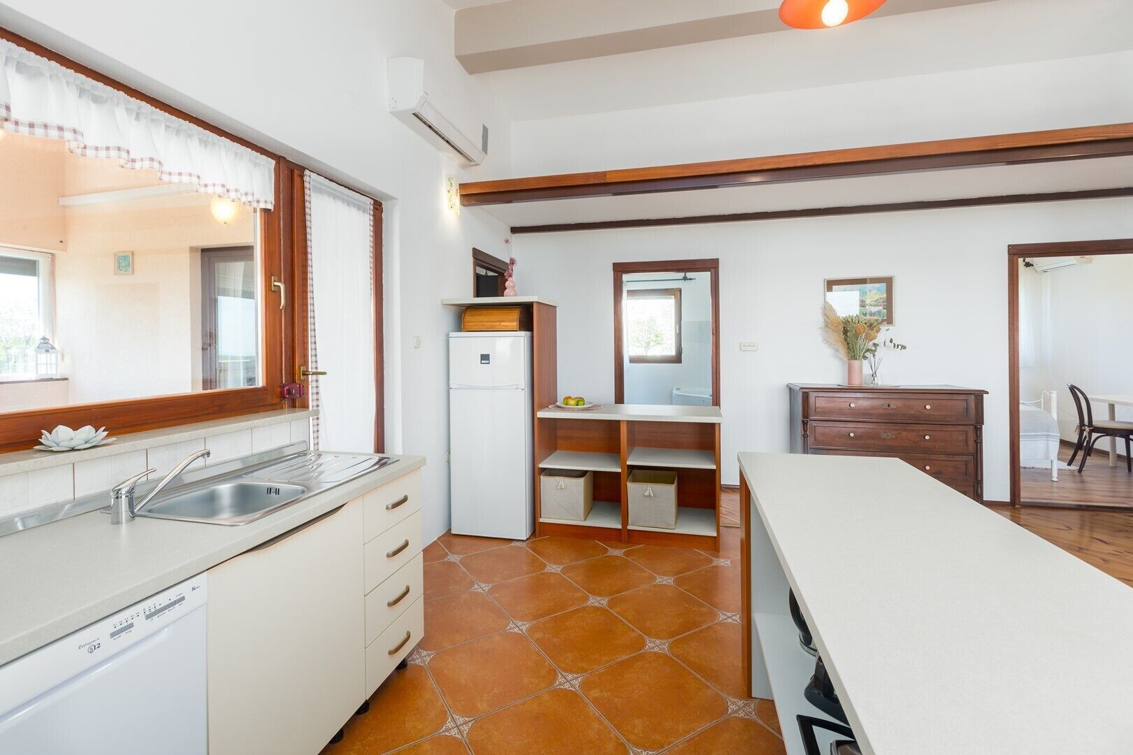 A compact kitchen with a dishwasher, a refrigerator, and a dining area with a table and chairs.