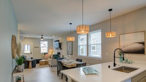 A modern kitchen with a large island, pendant lighting, and a view to the dining area.