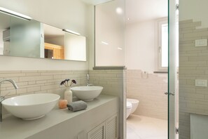 A modern bathroom with two sinks, a large mirror, and a glass shower enclosure. - Luxury Marignana By Geco Vacation Rentals (Camaiore)