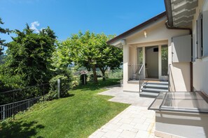 A modern house with a covered patio, a well-maintained lawn, and a view of the surrounding area. - Luxury Marignana By Geco Vacation Rentals (Camaiore)