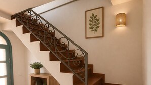 A staircase with a wrought iron railing, a wall-mounted light fixture, and a framed botanical print. - AMORE RENTALS - Casa Laura with Sea View Terrace (Positano)
