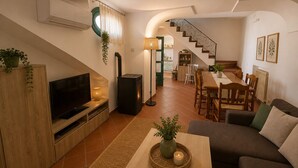 A living room with a TV, sofa, coffee table, and a staircase leading to a dining area. - AMORE RENTALS - Casa Laura with Sea View Terrace (Positano)