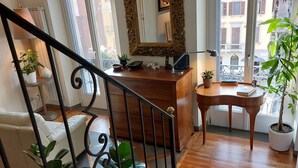 A staircase leading to a living area with a wooden desk, a mirror, and potted plants.