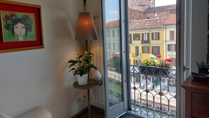 A balcony with a wrought iron railing, a potted plant, and a view of colorful buildings.
