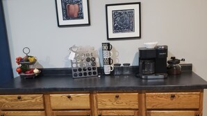 Una encimera de cocina con una cafetera, un frutero y un soporte para tazas de café.