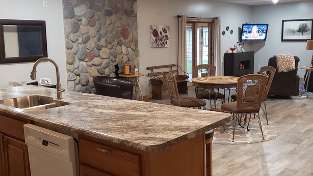 Una cocina amplia con encimera de granito, armarios de madera y una pared decorativa de piedra.