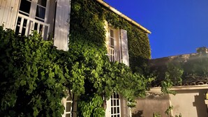 Un bâtiment dont les murs sont recouverts de lierre et dont les fenêtres sont dotées de volets.