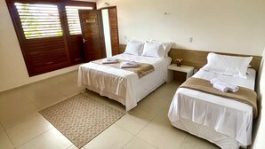A hotel room with two beds, a small table, a nightstand, a patterned rug, and a door with a sign.