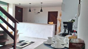 A modern kitchen with a dining area, a staircase, and a refrigerator.