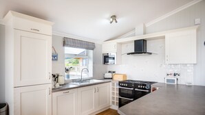 Een moderne keuken met witte kasten, een inbouwoven, een magnetron en een gasfornuis.