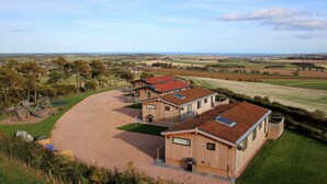 Una casa moderna con un amplio camino de entrada, un patio de juegos cercado y amplias vistas al campo.