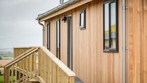 Een houten gebouw met een trap die naar een terras leidt.