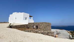 Un edificio blanco con muro de piedra y vista al mar.