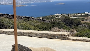 Vista de una playa con mar azul cristalino, terreno rocoso y un muro de piedra.