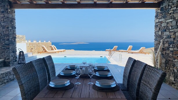 Una mesa de madera lista para comer con vista al mar.