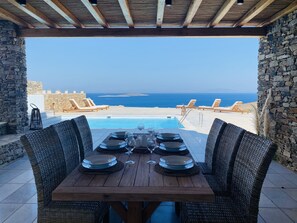 A wooden table set for dining with a view of the sea.