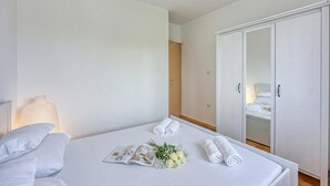 Un lit bien fait, avec des serviettes pliées, un magazine et un bouquet de fleurs.