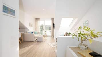 Ein modernes Apartment mit Wohnzimmer, Essbereich und einem Balkon mit Pflanze.