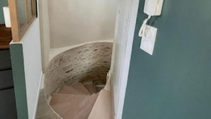 Una stretta scala con una parete strutturata e un soffitto con travi in legno.