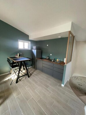 A compact kitchen with a dining area, featuring a small window, a refrigerator, and a sink.