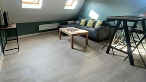 Una camera in stile loft con soffitto spiovente, due lucernari, un divano, un tavolino da caffè e una piccola scrivania.