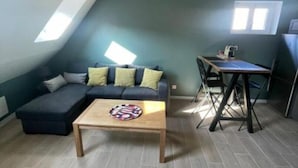 Una stanza in stile loft con una parete verde scuro a contrasto, un divano modulare, un piccolo tavolino e una scrivania pieghevole.