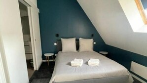 Una camera da letto con un letto, due comodini, una lampada a sospensione e una finestra.