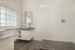 A bathroom with a white sink, a mirror, and a shower area.