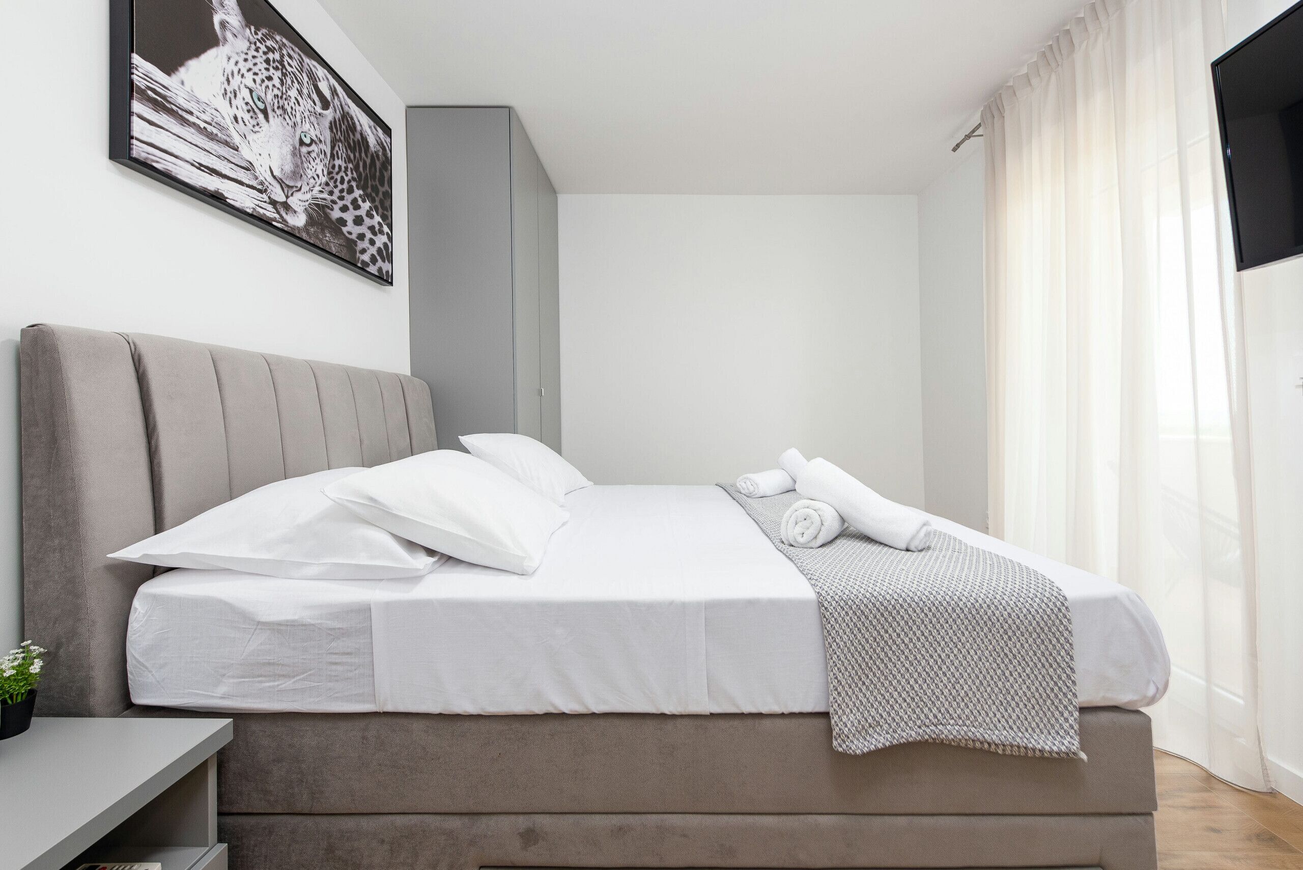 Une chambre moderne avec un grand lit, une table de chevet et une œuvre d’art accrochée au mur.