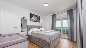 Une chambre à coucher comprenant un lit, une table de chevet, un miroir, une fenêtre avec des rideaux et une vue sur l’extérieur.